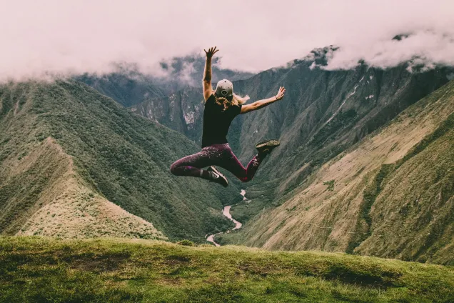 person jumping on a mountain 